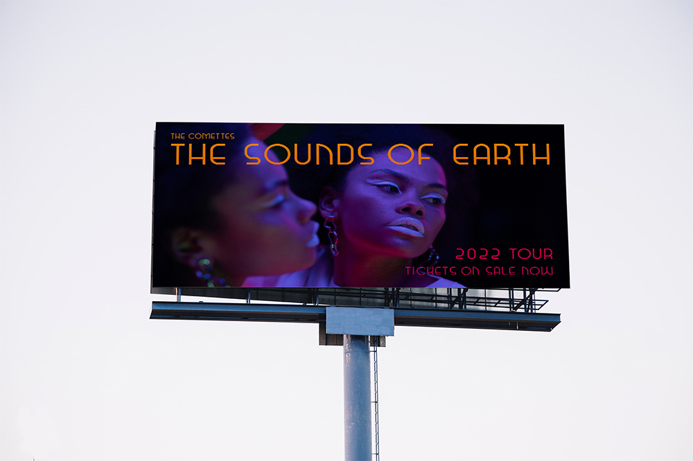 A billboard showing a Black woman looking into a mirror with dramatic makeup and lighting. The text on the billboard reads: The Comettes. The Sounds of Earth. 2022 Tour. Tickets on Sale Now.